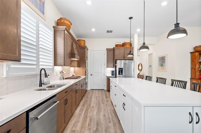 kitchen with a breakfast bar, white cabinets, sink, appliances with stainless steel finishes, and decorative light fixtures