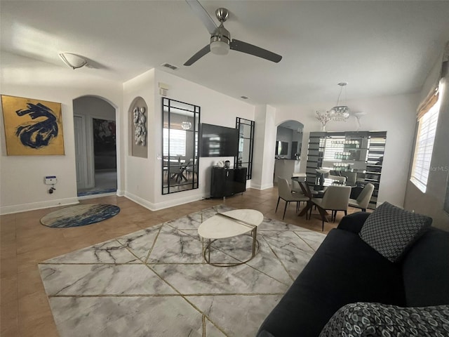 living room featuring tile flooring and ceiling fan with notable chandelier