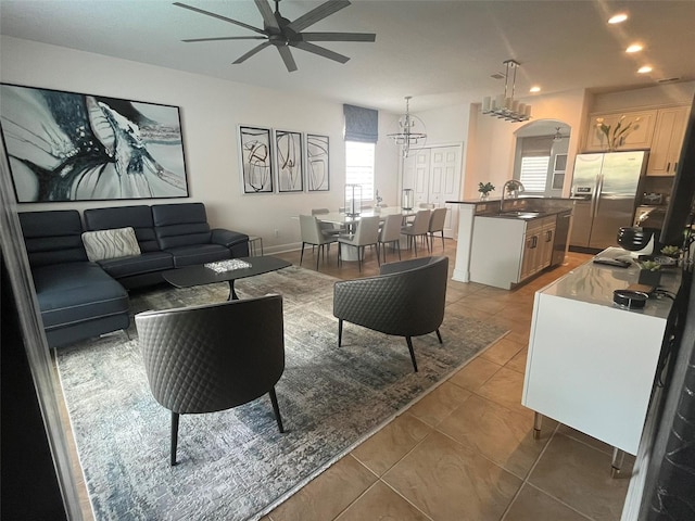 tiled living room featuring sink and ceiling fan with notable chandelier