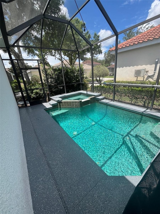 view of pool featuring glass enclosure and an in ground hot tub