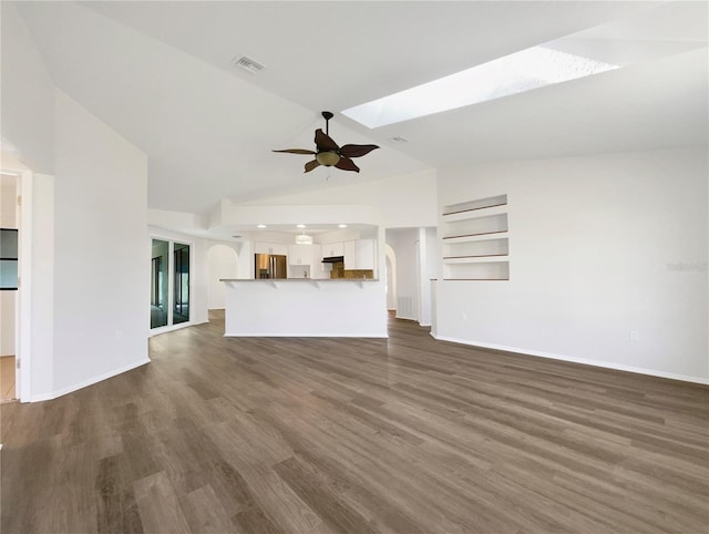 unfurnished living room featuring ceiling fan, built in features, dark wood-type flooring, and lofted ceiling with skylight