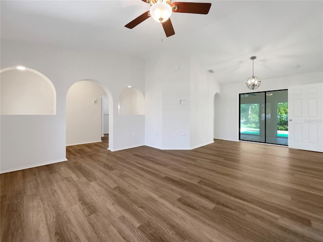 unfurnished living room with ceiling fan with notable chandelier and dark hardwood / wood-style flooring