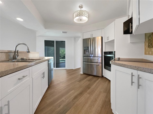 kitchen with white cabinets, sink, appliances with stainless steel finishes, and hardwood / wood-style floors