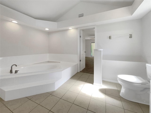 bathroom with tile patterned floors, vaulted ceiling, ceiling fan, a relaxing tiled tub, and toilet