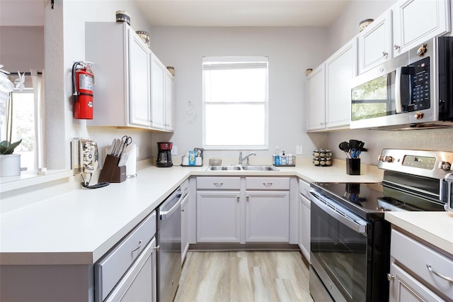 kitchen featuring white cabinets, sink, stainless steel appliances, and light hardwood / wood-style flooring