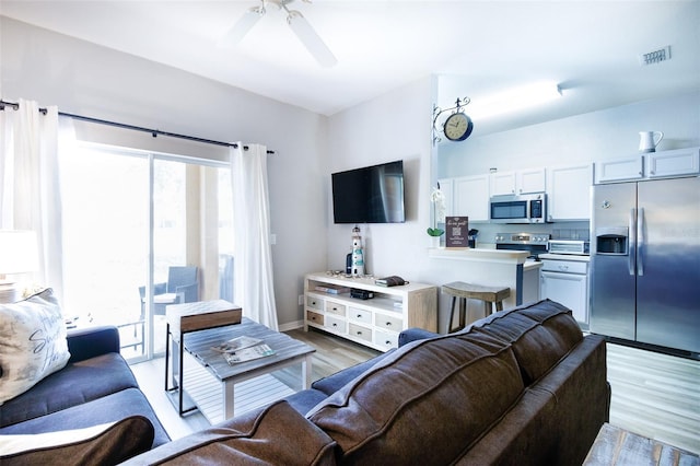 living room featuring ceiling fan and light hardwood / wood-style flooring