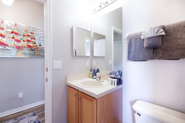 bathroom with hardwood / wood-style flooring, toilet, and vanity