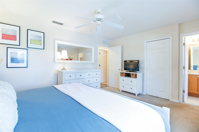 bedroom with light carpet, ceiling fan, a closet, and ensuite bath