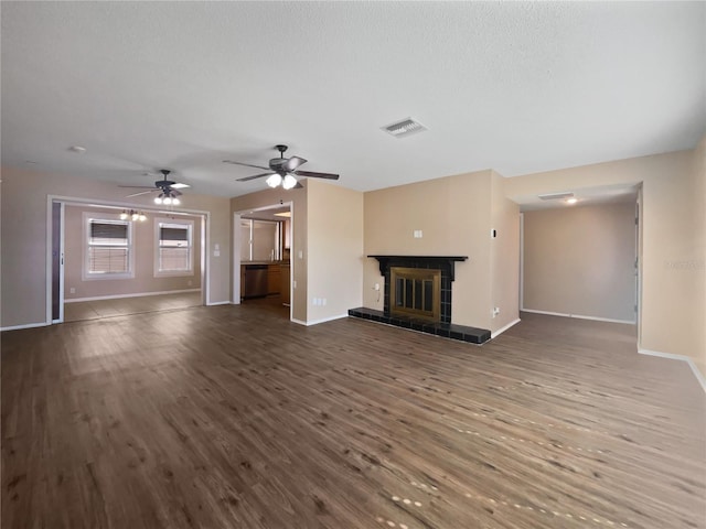 unfurnished living room featuring dark hardwood / wood-style flooring, ceiling fan, a tile fireplace, and a textured ceiling