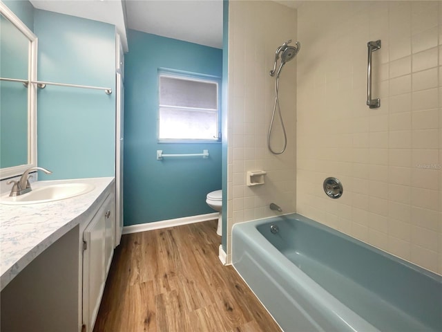 full bathroom with hardwood / wood-style flooring, vanity, toilet, and tiled shower / bath combo