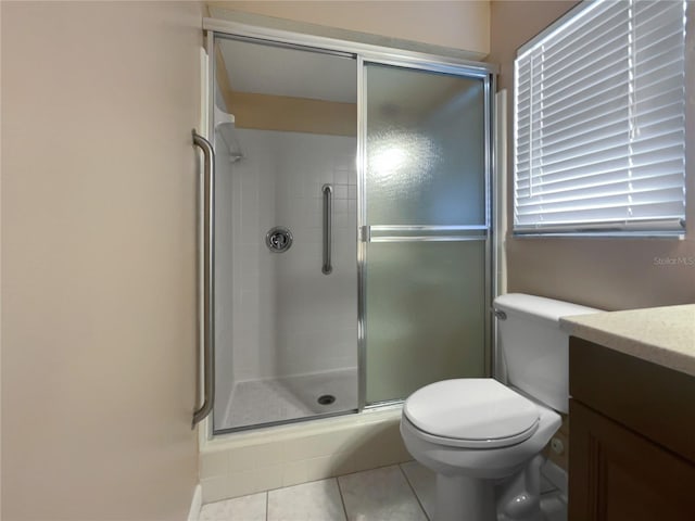 bathroom featuring tile patterned flooring, vanity, a shower with door, and toilet