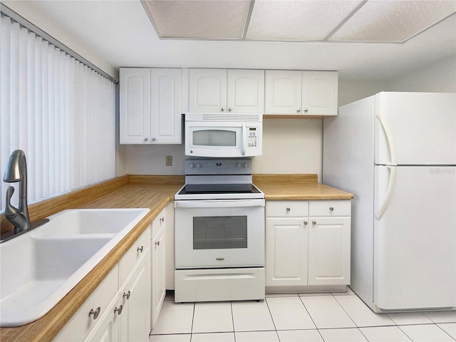 kitchen with white cabinetry, sink, light tile patterned floors, and white appliances