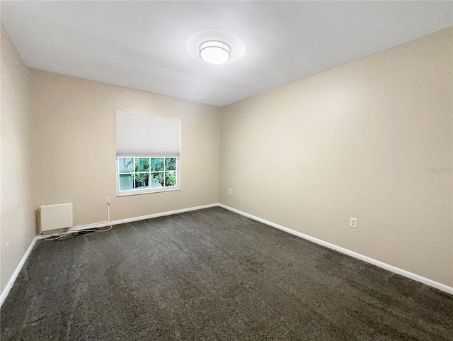 spare room featuring dark carpet