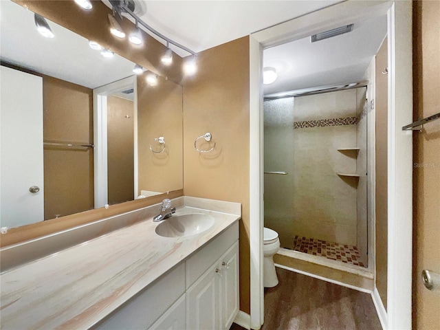 bathroom with hardwood / wood-style floors, vanity, toilet, and a shower with shower door