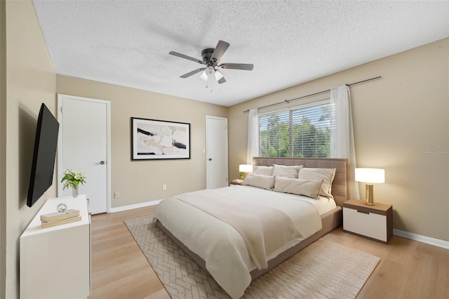 bedroom with light wood-type flooring, ceiling fan, and a textured ceiling