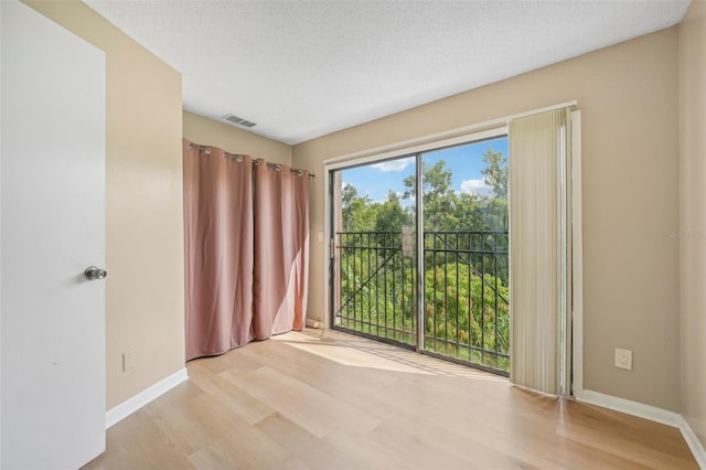 unfurnished room featuring light hardwood / wood-style flooring and a textured ceiling