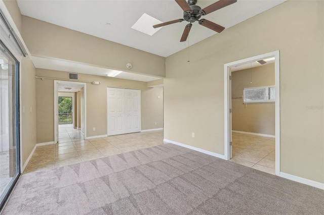 unfurnished room featuring ceiling fan, a skylight, and light tile patterned flooring