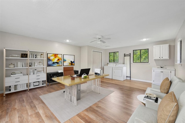 office featuring washer and dryer, light hardwood / wood-style floors, sink, and ceiling fan