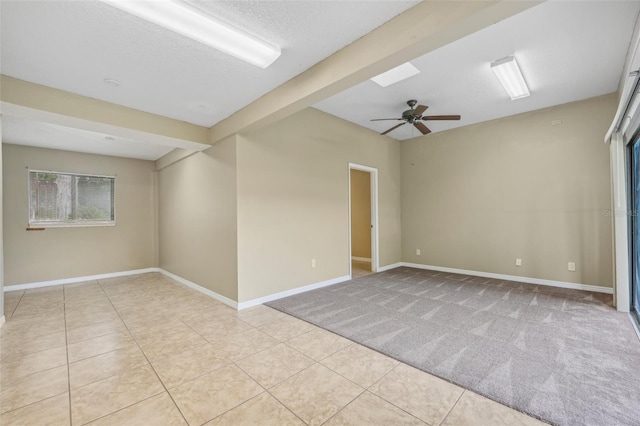 tiled spare room with ceiling fan, beamed ceiling, and a textured ceiling