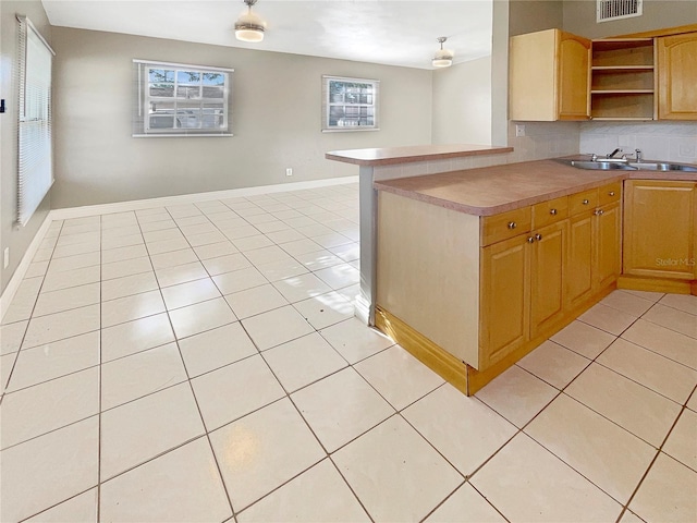 kitchen featuring kitchen peninsula, sink, light tile patterned flooring, and plenty of natural light