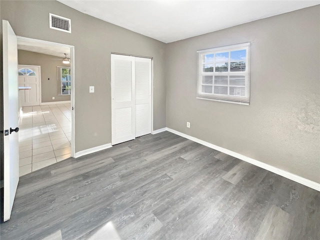 unfurnished bedroom featuring multiple windows, dark hardwood / wood-style floors, and a closet