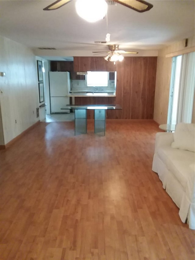 kitchen featuring brown cabinetry, light wood-type flooring, freestanding refrigerator, open floor plan, and a center island