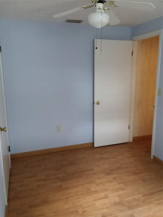 unfurnished room featuring visible vents, light wood-style flooring, baseboards, and a ceiling fan