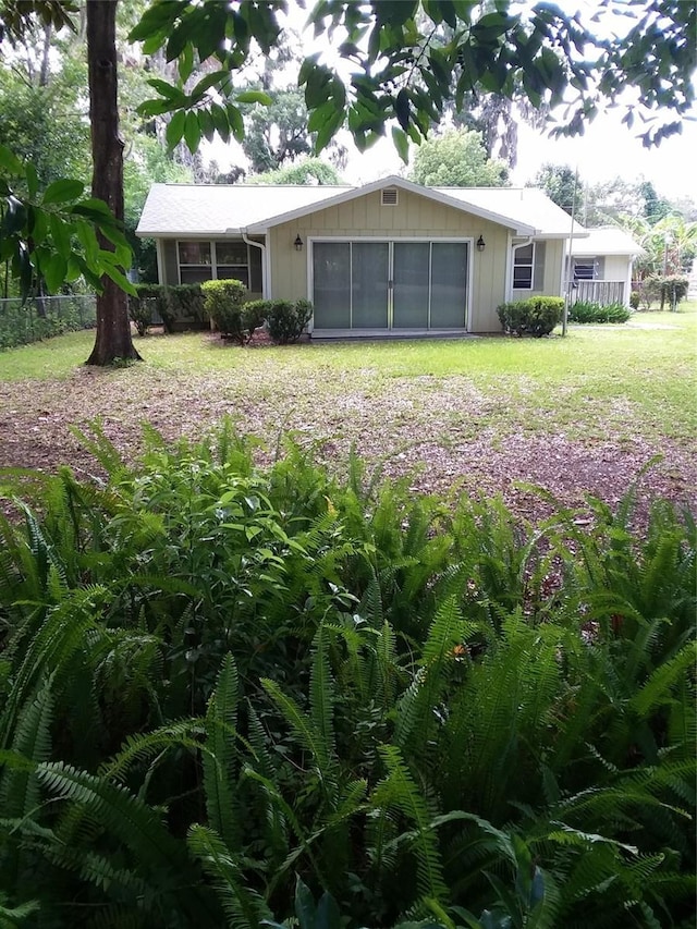 view of front facade with a front yard, an attached garage, fence, and board and batten siding