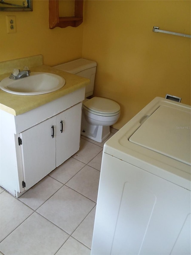 bathroom with washer / clothes dryer, toilet, vanity, and tile patterned flooring