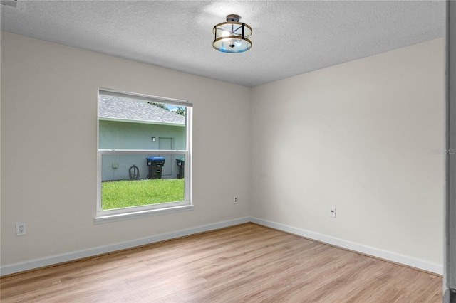 unfurnished room with light hardwood / wood-style flooring, a healthy amount of sunlight, and a textured ceiling