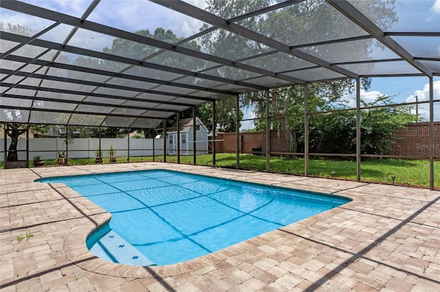 view of pool featuring glass enclosure, a patio area, a storage shed, and a yard