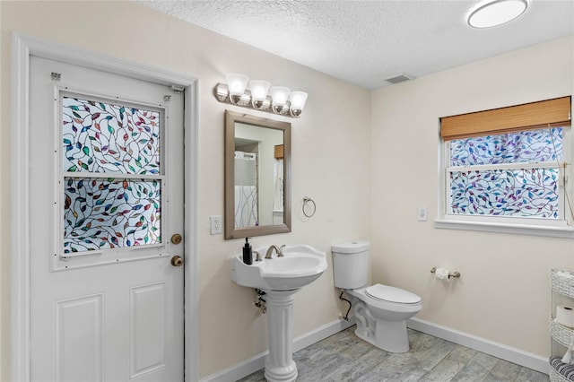 bathroom with hardwood / wood-style floors, a textured ceiling, and toilet