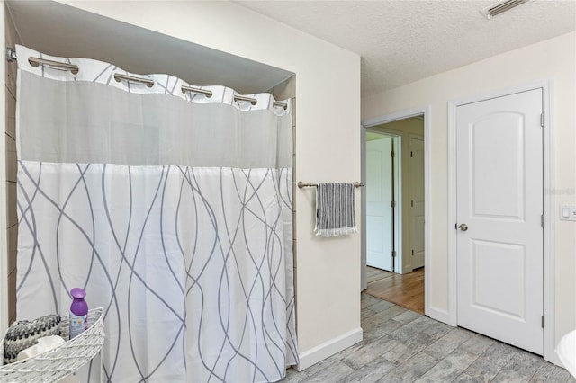 bathroom featuring hardwood / wood-style floors, a textured ceiling, and curtained shower