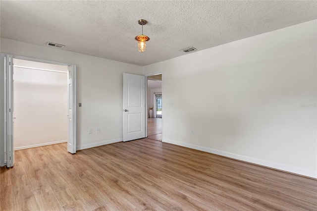 unfurnished bedroom with light wood-type flooring and a textured ceiling