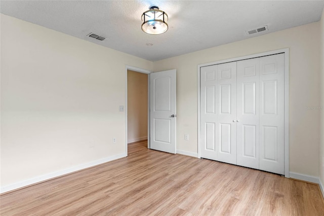 unfurnished bedroom featuring a textured ceiling, light hardwood / wood-style flooring, and a closet