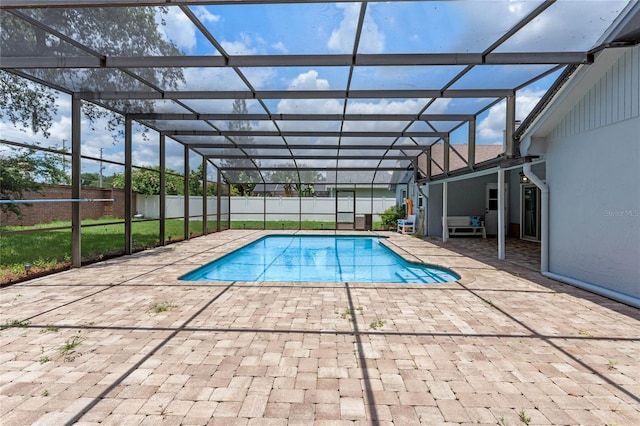 view of pool with glass enclosure, a yard, and a patio