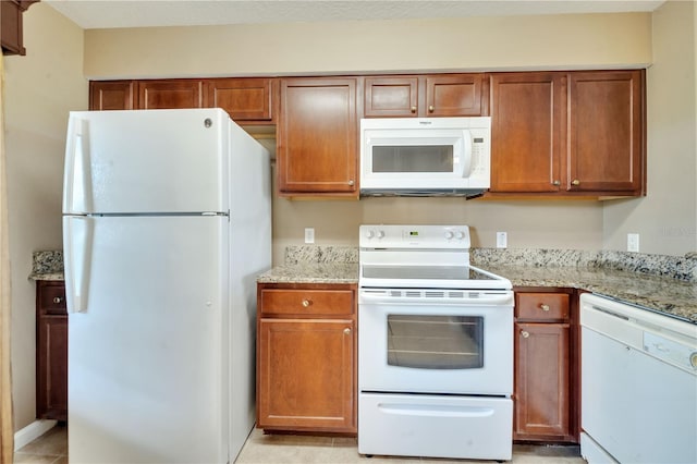 kitchen featuring light tile patterned floors, light stone counters, and white appliances