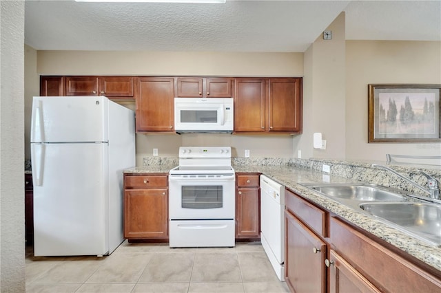 kitchen with white appliances, sink, light tile patterned floors, a textured ceiling, and light stone countertops