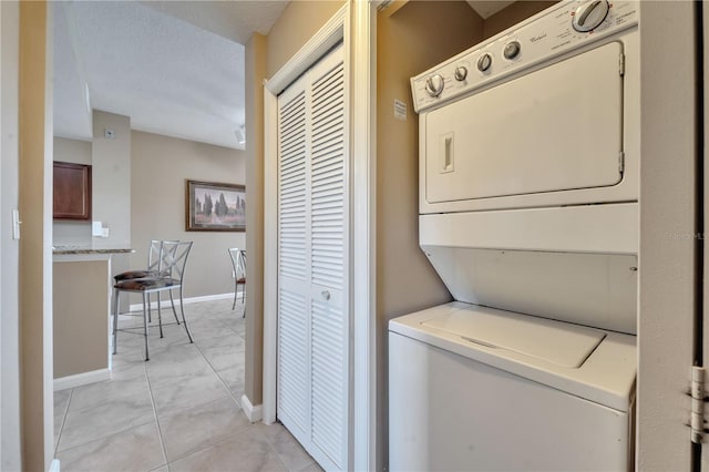 laundry room featuring stacked washer and clothes dryer and light tile patterned floors