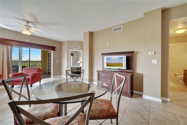 tiled dining room with a textured ceiling and ceiling fan