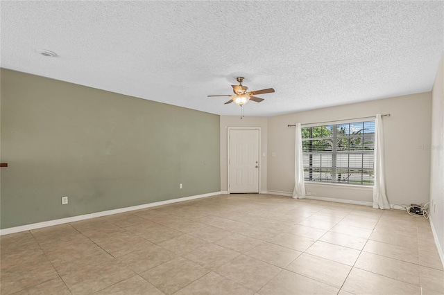 empty room featuring light tile patterned floors, baseboards, a textured ceiling, and ceiling fan