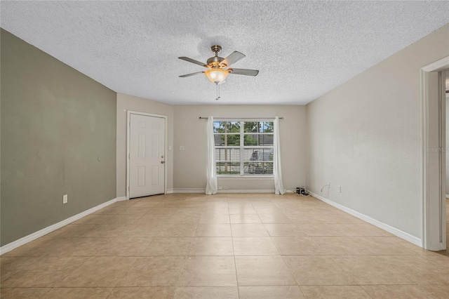 empty room with light tile patterned flooring, a textured ceiling, baseboards, and a ceiling fan