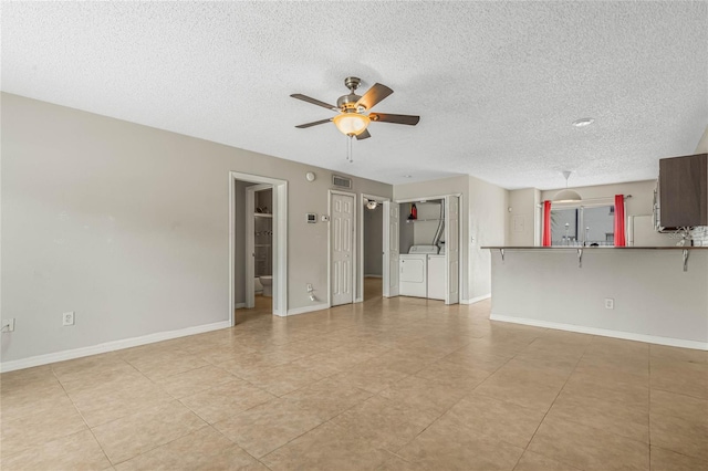 unfurnished living room featuring separate washer and dryer, a textured ceiling, ceiling fan, and light tile floors