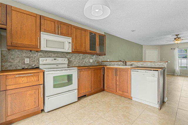 kitchen with backsplash, brown cabinets, a peninsula, white appliances, and a sink