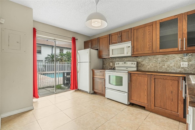 kitchen with white appliances, tasteful backsplash, light tile patterned flooring, and brown cabinetry