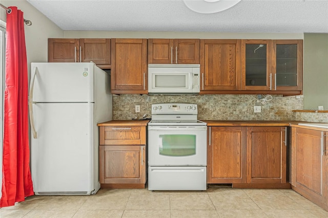 kitchen featuring backsplash, a textured ceiling, white appliances, and light tile floors