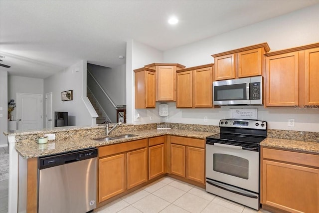 kitchen with light stone counters, light tile patterned flooring, appliances with stainless steel finishes, sink, and kitchen peninsula