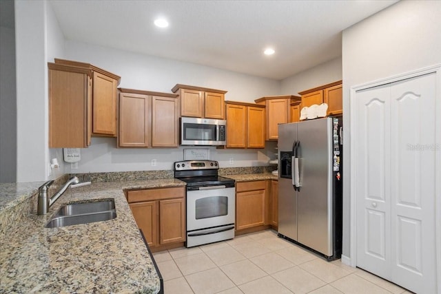 kitchen featuring light tile patterned floors, sink, light stone counters, and appliances with stainless steel finishes