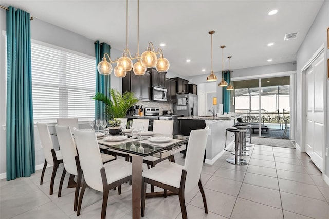 dining area with sink, an inviting chandelier, and light tile flooring