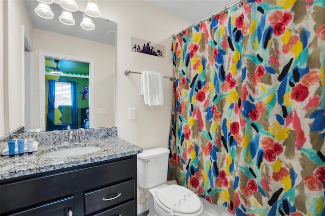 bathroom with ceiling fan, toilet, and vanity with extensive cabinet space